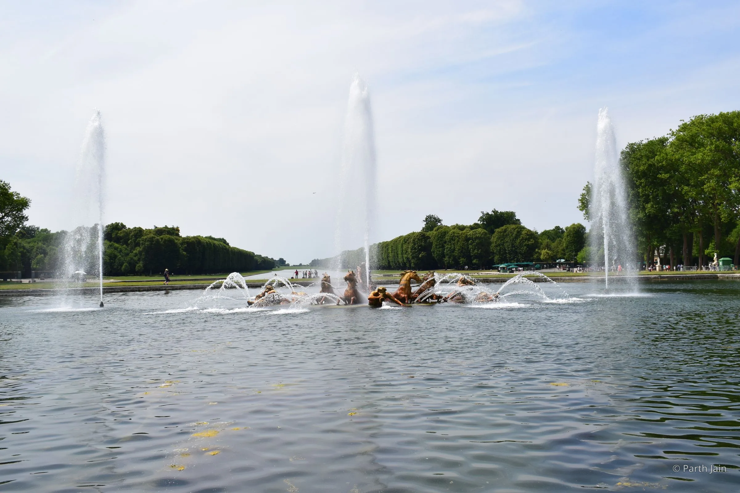 The Apollo fountain at Versailles in full play, Apollo's chariot rising from the basin with horses, water arcing on either side.