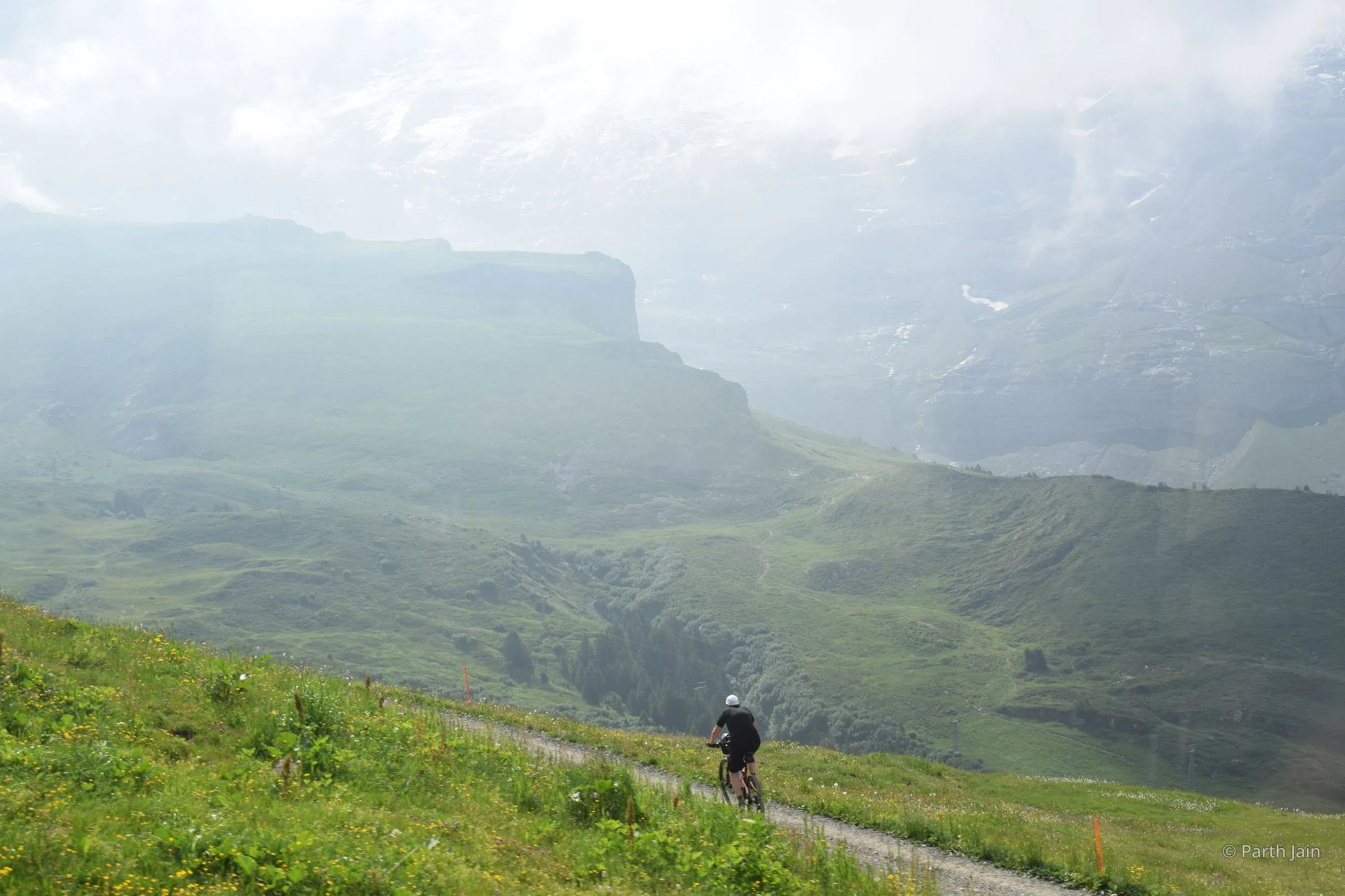 A lone cyclist riding along a mountain road in the morning.