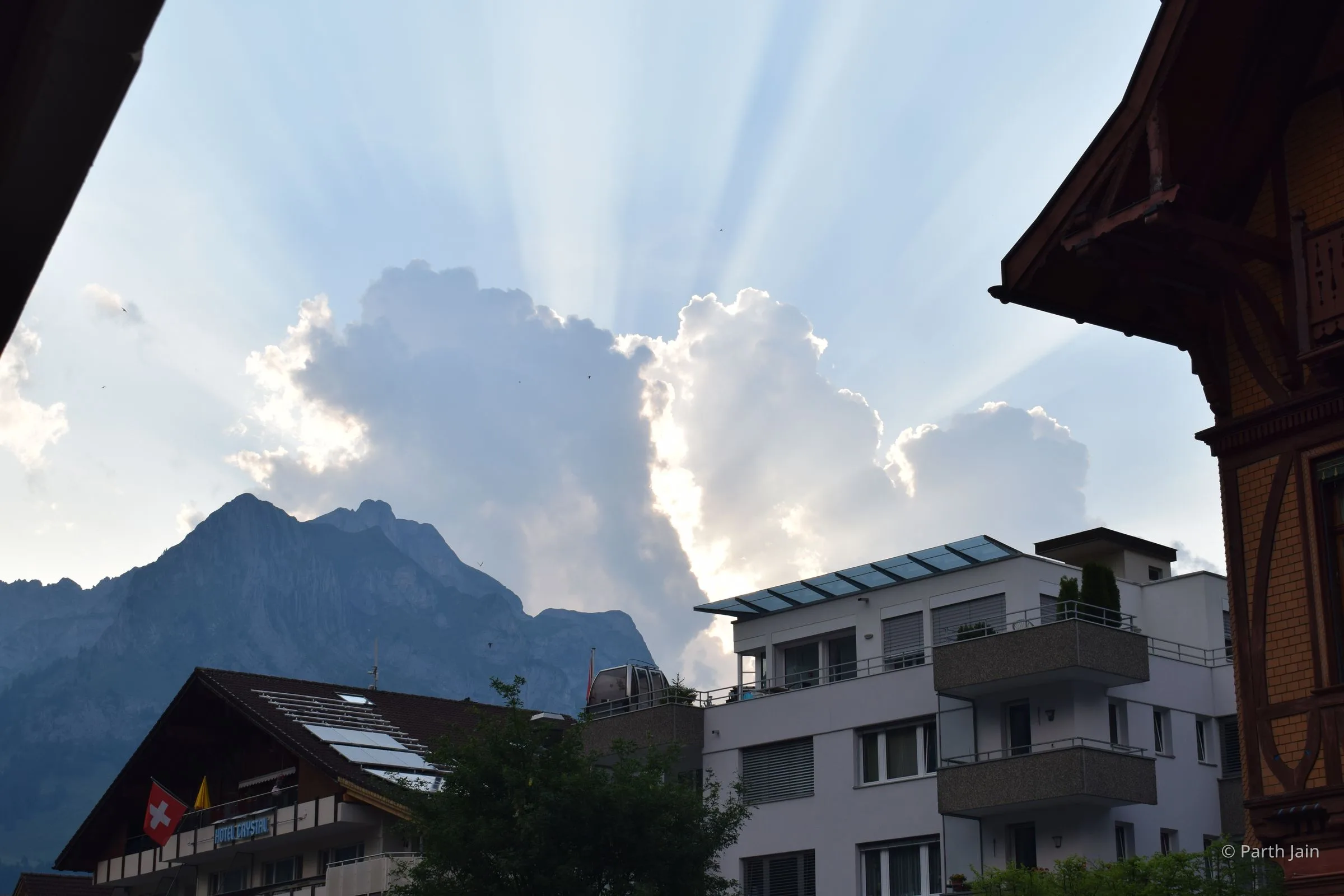 Sunrays cutting through cloud over an Alpine balcony view.
