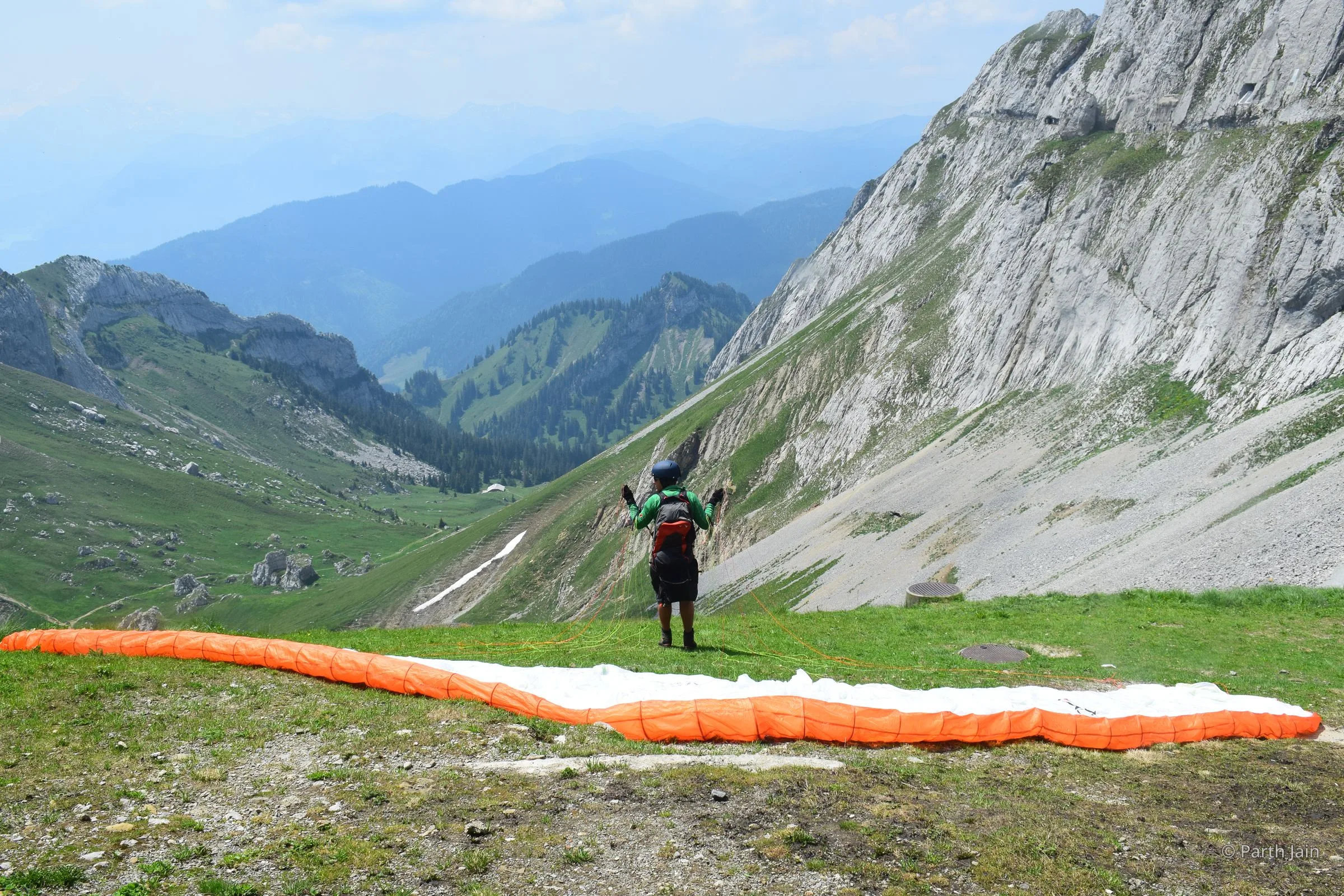 A paraglider running off the launch slope on Mt. Pilatus, canopy filling above.